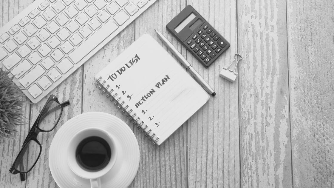 Coffee cup and notebook with to do list on wooden table